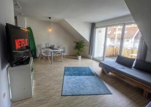 sala de estar con sofá, TV y mesa en Über den Dächern von Kirchheim, Modernes Apartment en Kirchheim unter Teck