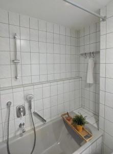 キルヒハイム・ウンター・テックにあるÜber den Dächern von Kirchheim, Modernes Apartmentの白いタイル張りのバスルーム(鉢植えのバスタブ付)