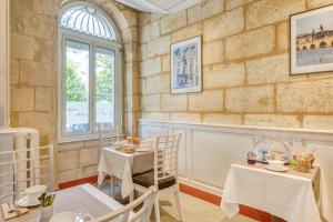 une salle à manger avec deux tables et une fenêtre dans l'établissement Hôtel des Voyageurs Centre Bastide, à Bordeaux