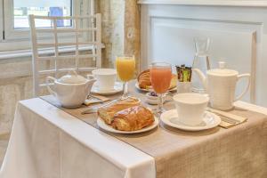 a table with a breakfast of croissants and orange juice at Hôtel des Voyageurs Centre Bastide in Bordeaux