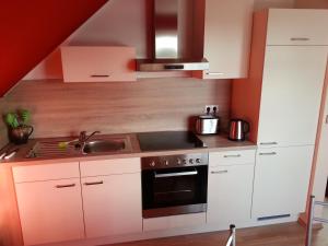 a kitchen with white cabinets and a stove top oven at ferienwohnung mertens in Westerstede