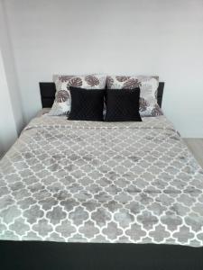 a bed with a gray and white comforter and pillows at Apartamencik na Doby - Lubin in Lubin