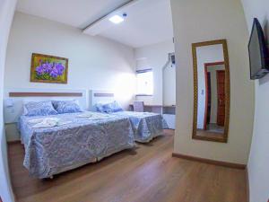 a bedroom with two beds and a mirror at HOTEL LAGO ARARAS in Araras