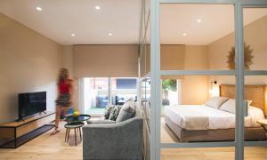 een vrouw die door een slaapkamer loopt met een bed en een tv bij Terraza Playa de Cádiz 1 Ha Apartment in Cádiz