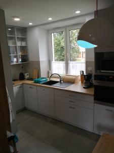 eine Küche mit weißen Schränken, einem Waschbecken und einem Fenster in der Unterkunft Apartament Stok o krok in Stronie Śląskie
