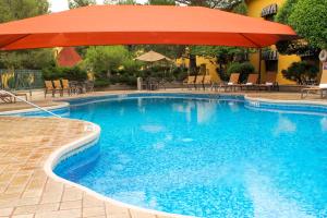 uma piscina com guarda-sol, cadeiras e mesas em Holiday Inn Express Chihuahua, an IHG Hotel em Chihuahua