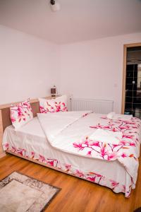 a bedroom with a large bed with pink flowers on it at Pensiunea Happy Flowers in Greci +91 photos