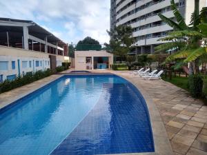 a swimming pool with chairs and a building at Verano Praia Ponta Negra AP 1401 in Natal