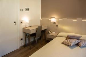 1 dormitorio con cama, escritorio y mesa en Albergo Milano, en Darfo Boario Terme