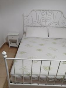 a white bed with a metal bed frame and a nightstand at Casa Maris in Santo Stefano di Camastra