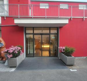 a red building with a glass door and flowers at Hotel Da Sabino in Singen