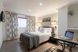 a bedroom with a bed and a laptop on a desk at Hotel Picasso Inn in Bogotá