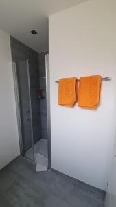2 toallas naranjas colgadas en la pared del baño en Chambre d'hôte "Minergy", en Donatyre