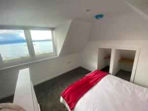 a white room with a bed with a red blanket at The Wee Cottage by the Ferry in Gourock