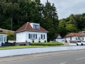 a white house with a red roof on a street at The Wee Cottage by the Ferry in Gourock