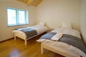 twee bedden in een kleine kamer met een raam bij Hakuba Shiro Usagi - Vacation STAY 87281 in Hakuba