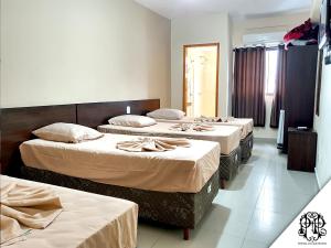 a group of three beds in a room at Portal Palace Hotel in Aparecida