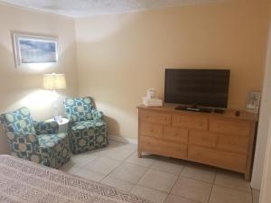 Una sala de estar con un televisor y una silla. en Pennwood Motor Lodge, en Sebastian