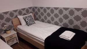 małe łóżko w pokoju ze ścianą w obiekcie Apartament Villa Magnolia w Oświęcimiu