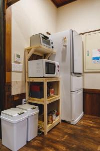 uma cozinha com um frigorífico e um micro-ondas numa prateleira em Couch Potato Hostel - Vacation STAY 88243 em Matsumoto