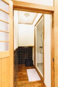 uma casa de banho com um espelho e um chuveiro com azulejos pretos em Couch Potato Hostel - Vacation STAY 88243 em Matsumoto