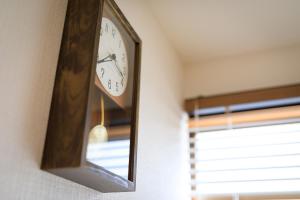 a clock hanging on a wall next to a window at hiyohiyo in Kanazawa