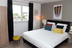 - une chambre avec un grand lit blanc et un tabouret jaune dans l'établissement Home Place Apartments - Langon Sauternes, à Langon