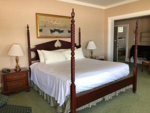 1 dormitorio con 1 cama grande con marco de madera en Sands Of Time Motor Inn & Harbor House, en Woods Hole