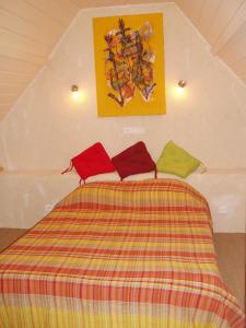 1 dormitorio con 1 cama con almohadas rojas y verdes en Gîte de La Porte du Parc en Les Iffs