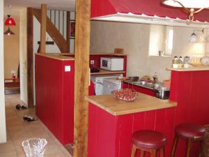 a kitchen with red cabinets and a counter with stools at Gîte de La Porte du Parc in Les Iffs