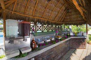 an outdoor kitchen with a grill and a thatched roof at Vista Playa de Oro Manzanillo in Manzanillo