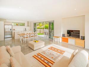 a living room with a white couch and a kitchen at A Slice of Summer - Whangapoua Holiday Home in Whangapoua