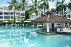 a swimming pool with a hut in the middle of a resort at Peppers Beach Club & Spa in Palm Cove