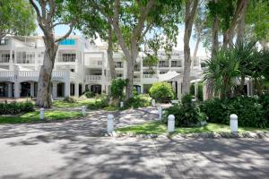 un gran edificio blanco con árboles delante de él en Peppers Beach Club & Spa en Palm Cove