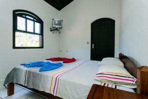 1 dormitorio con 1 cama con 2 toallas en Ilhabela, charmosos chalés com ótima localização, en Ilhabela