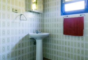 baño con lavabo, ventana y toalla roja en Ilhabela, charmosos chalés com ótima localização, en Ilhabela