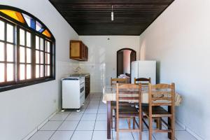 cocina con mesa, sillas y nevera en Ilhabela, charmosos chalés com ótima localização, en Ilhabela