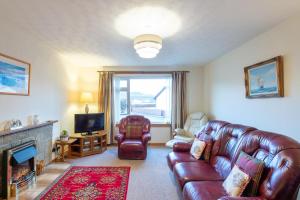 a living room with a leather couch and a television at Clisham in Beauly