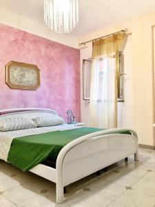 a bedroom with a bed and a pink wall at Appartamento Maria Giovanna in Giardini Naxos