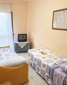 a room with two beds and a tv in it at Appartamento Maria Giovanna in Giardini Naxos
