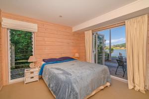 ein Schlafzimmer mit einem Bett und einem großen Fenster in der Unterkunft Opoutere Oasis - Opoutere Holiday Home in Opoutere