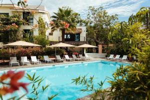 una piscina frente a un hotel con sillas y sombrillas en San Trópico Boutique Hotel & Peaceful Escape en Puerto Vallarta