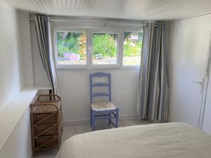 a bedroom with a bed and a chair and two windows at INTERLUDE omaha beach 50 m de la plage in Saint-Laurent-sur-Mer