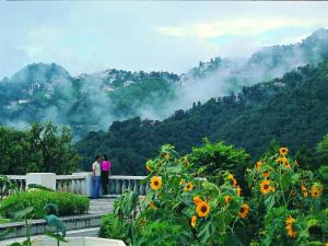 two people standing on a balcony looking at the mountains at Jaypee Residency Manor in Mussoorie