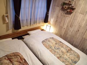 Dos camas en una habitación pequeña con ventana. en Kyoto Villa Kotone, en Kioto