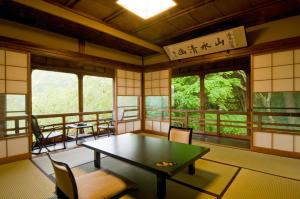 a room with a table and chairs and windows at Hakone Kowakien Mikawaya Ryokan in Hakone