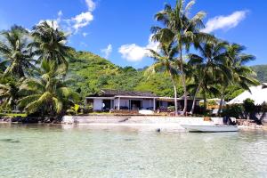 une maison sur la plage avec des palmiers et un bateau dans l'établissement Villa Oona, à Maharepa