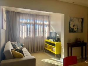 a living room with a couch and a television at Flat Blumenau Vila Nova in Blumenau