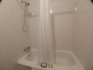 a white bath tub sitting under a shower curtain at Wessex Inn By The Sea in Cowichan Bay
