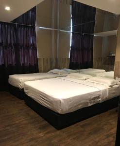 two beds in a hotel room with white sheets at Time Hotel in Seremban